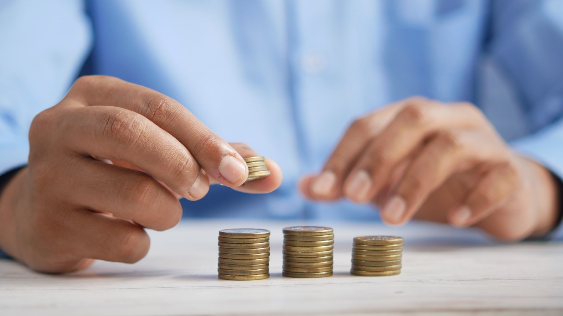 A man stacks coins on a table.