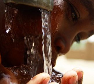 Ребенок пьет воду из-под крана
